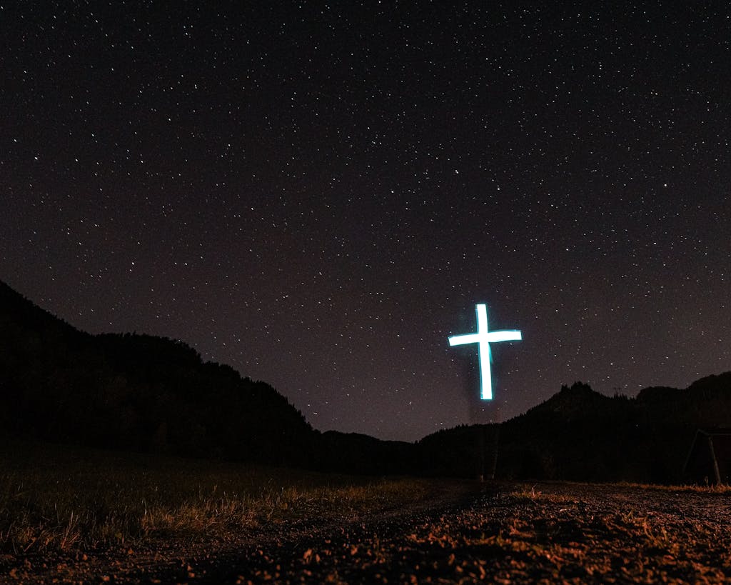 A scenic night view with a glowing cross under a starry sky, evoking spirituality.