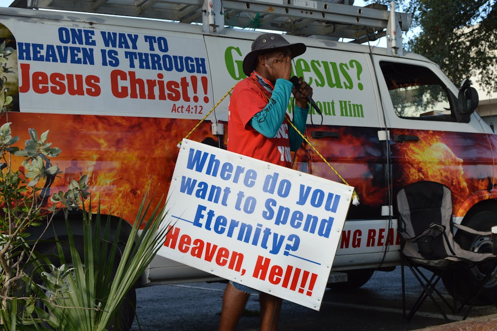A street preacher delivers a message about salvation and eternity with a bold van poster.