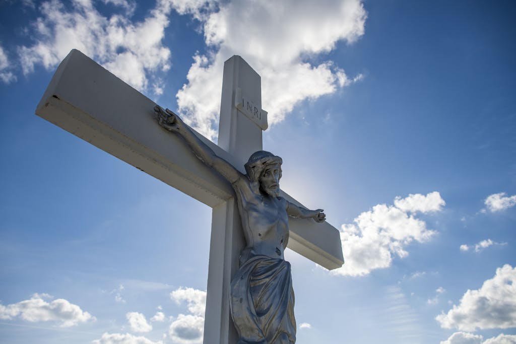 A striking sculpture of Jesus on the cross with a vivid blue sky background.