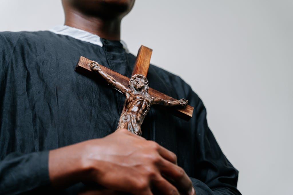 Person in religious attire holding a crucifix, symbolizing faith and belief.